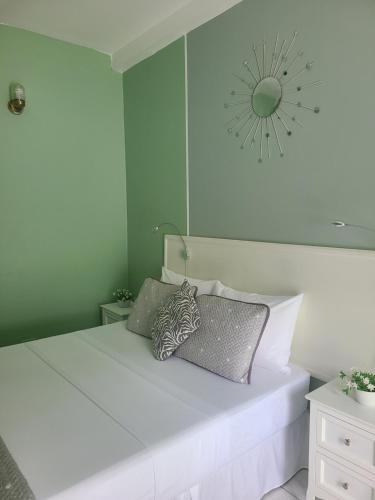a bedroom with a white bed with a clock on the wall at Riverside Poolside Apartment in San Juan