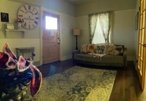 a living room with a couch and a clock on the wall at IreneHouse Victorian INN in Sacramento