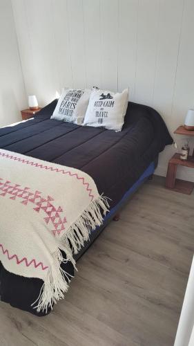 ein Bett mit einer Decke und Kissen darauf in der Unterkunft Casa ZenPine in San Martín de los Andes