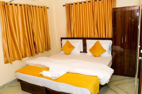 a bedroom with two beds with orange curtains at Sunflower Inn in kolkata