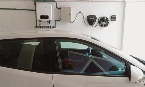 a white car parked in a garage with a car charger at Casa Dulé, a poucos metros da praia in Guarapari