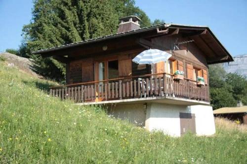 a house with a balcony with an umbrella at Charmant petit chalet cosy in Combloux