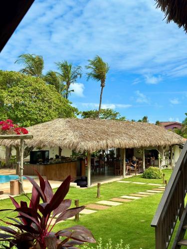 a resort with a straw roof and a pool at Pousada Casa Caju Bangalows in Cumbuco