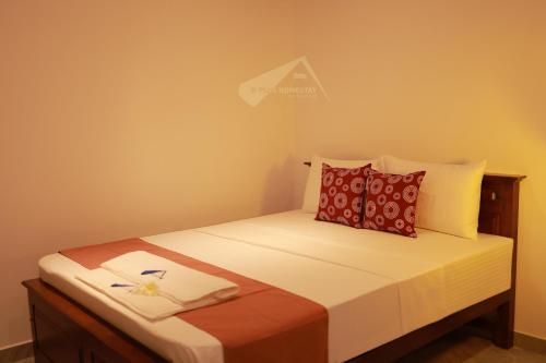 a small bedroom with a bed with red pillows at D Plus Homestay Negombo in Negombo