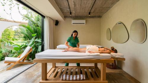 a woman sitting on a bed in a room at Hotel Palo Cruz in Villavicencio