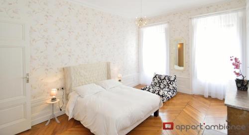 a white bedroom with a bed and a chair at Appart' Odeon in Lyon