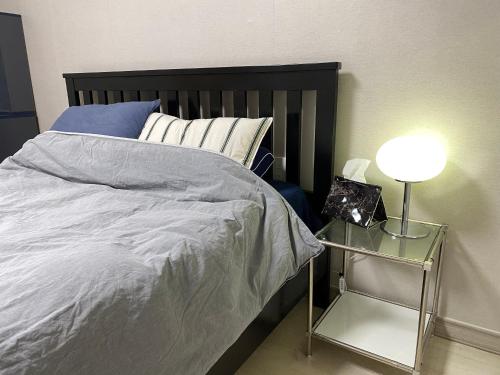 a bed with a black headboard and a table with a lamp at 스테이 휴가 의정부점 in Uijeongbu