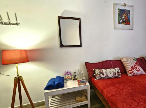 a living room with a red couch and a lamp at Frozen Monks in Kodaikānāl