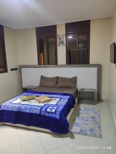 a bedroom with a bed with a blue comforter at Welcome Hôtel Dijon in Ouzoud