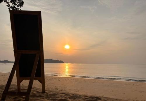 an easel on the beach with a sunset at Sunny Cove Beach Resort Koh Phayam in Ranong