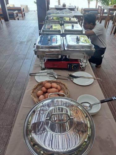 a buffet line with plates and eggs on a table at Sunny Cove Beach Resort Koh Phayam in Ranong