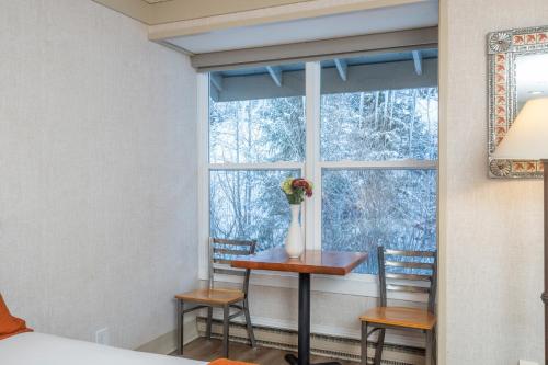 a window with a table and two chairs and a vase with flowers at Mountainside Inn 418 by Alpine Lodging Telluride in Telluride