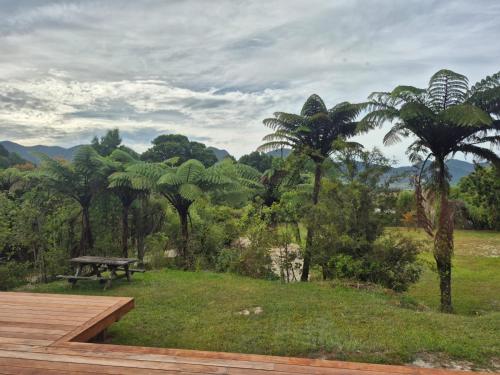a wooden deck with a picnic table and palm trees at Modern Comfort in Collingwood - Brand New Holiday Home in Collingwood