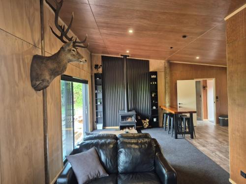 a living room with a leather couch and a deer head on the wall at Modern Comfort in Collingwood - Brand New Holiday Home in Collingwood