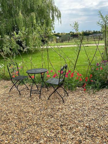 two chairs and a table in a park with flowers at The Cranny, 1 Bedroom House with Indoor Fireplace in Bicester