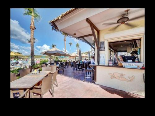 an outdoor restaurant with tables and chairs and palm trees at Dreamy Condo 2 minute walk to Beach w King Size Bd in Fort Pierce