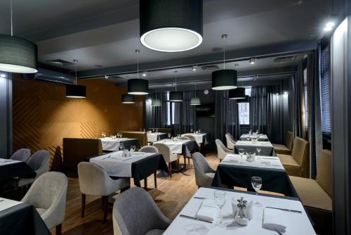 ノヴォシビルスクにあるPark Wood Hotel - Academgorodokの白いテーブルと椅子、照明が備わるレストラン