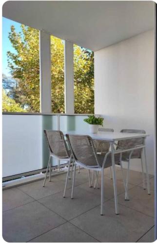 une table et des chaises blanches dans une chambre avec fenêtres dans l'établissement Appartement cocon, à Décines-Charpieu