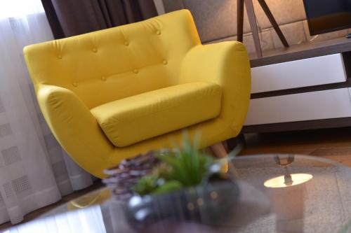 a yellow chair in a living room with a table at Boutique Rooms in Belgrade