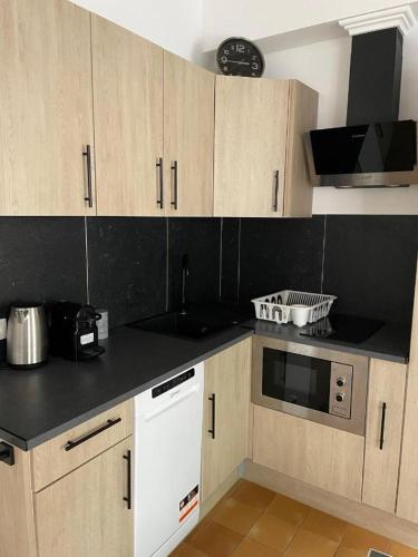 a kitchen with wooden cabinets and a black counter top at La Ferme du Château - Luxury Suite in Fontaine-lʼÉvêque