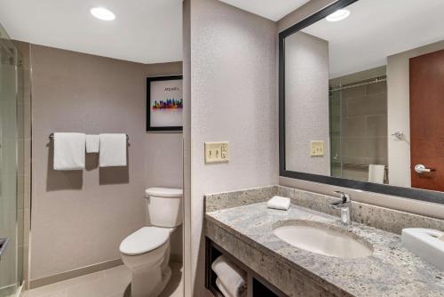 a bathroom with a toilet and a sink and a mirror at Drury Inn & Suites Atlanta Airport in Atlanta