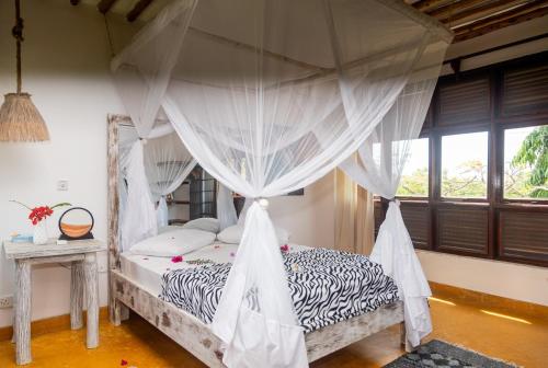 a bedroom with a canopy bed with mosquito nets at Serene 3 bed villa in the garden in Mombasa