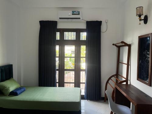 a room with a window with a green bed and a desk at Transit Terminal at colombo airport in Katunayake