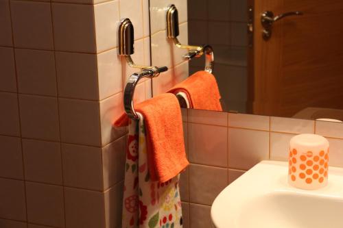 y baño con toallas de color naranja, lavabo y espejo. en Apartamento Homelife Toletum, en Toledo