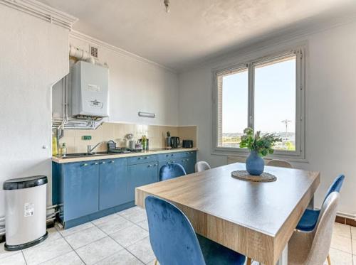 une cuisine avec une table en bois et des armoires bleues dans l'établissement Elegant Zola, à Villeurbanne