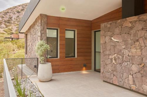 a house with a stone wall and a vase on a porch at Ayres Lodge Vista Calma Potrerillos in Potrerillos