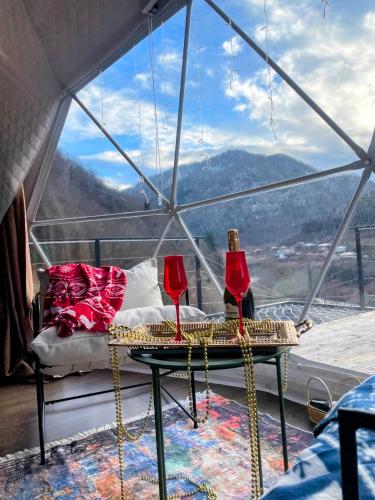 a room with two wine glasses on a table in front of a window at Glamping Daphenili in Tskalt'ashua