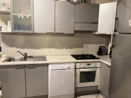 a kitchen with white cabinets and a stove and a sink at Gîte de France "les volets bleus" 3 épis - Gîte de France 12 personnes MAE-9484 in Espartignac