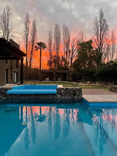 a swimming pool with a sunset in the background at Casa Prana in Ciudad Lujan de Cuyo