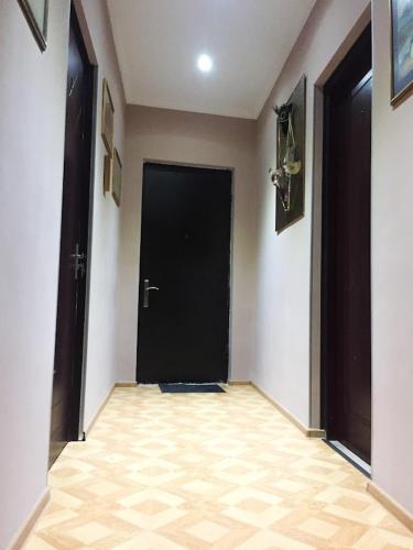 a hallway with a black door and a tile floor at The Sindh Hostel Tbilisi in Tbilisi City