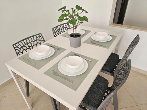 a white table with chairs and plates and a potted plant at La Esmeralda in Tetouan