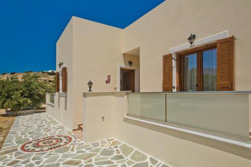 a white house with a tile floor and windows at Olive Studios Karpathos Studio #4 in Karpathos Town