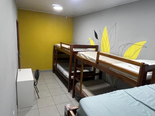 a room with three bunk beds and a yellow wall at Jambu Hostel Belém in Belém