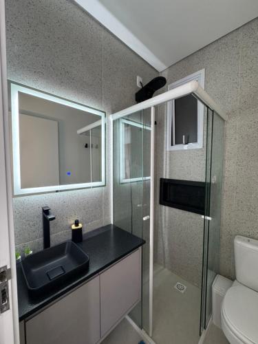 a bathroom with a sink and a glass shower at Studio no centro, confortável e prático in Florianópolis