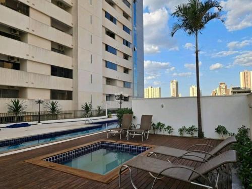 a patio with chairs and a swimming pool on top of a building at Apartamento 2 Dormitórios, Bueno in Goiânia