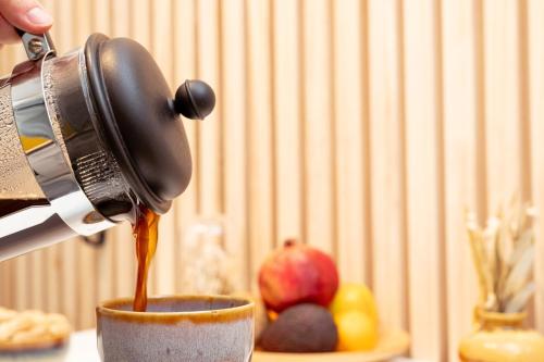 a person is pouring coffee into a cup at Nice Weekends Graz City Centre - Free Parking, Pets Welcome & Walk to Old Town - Mur - Kunsthaus in Graz