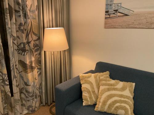 a living room with a blue couch and a lamp at Appartementen de Strandloper in Bergen aan Zee