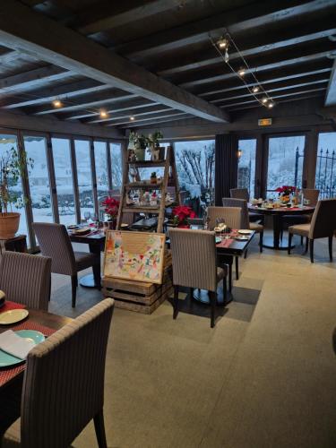 a dining room with tables and chairs and windows at Maison de Sisi in Ugine