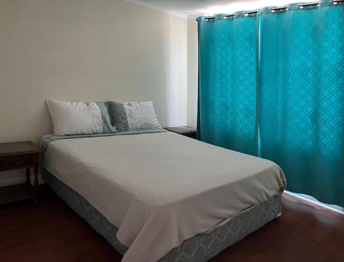 a bedroom with a bed with a blue curtain at Depto Boulevard del Sol II in Viña del Mar