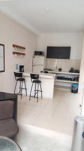 a kitchen with two bar stools and a counter at Casa de Ana - Habitación privada in Cancún