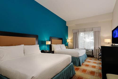 a hotel room with two beds and a blue wall at Holiday Inn Express & Suites Houston Northwest-Brookhollow by IHG in Houston