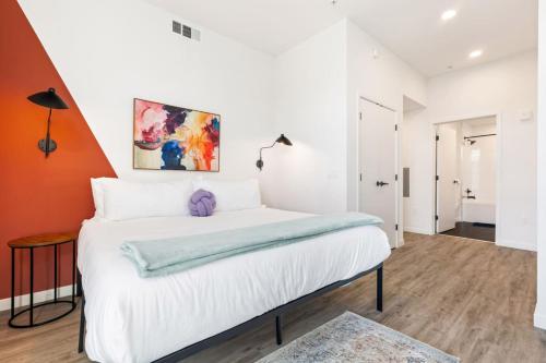 a bedroom with a large white bed with a painting on the wall at 2BD Modern DTLA Apartment Minutes from Dodger Stadium in Los Angeles