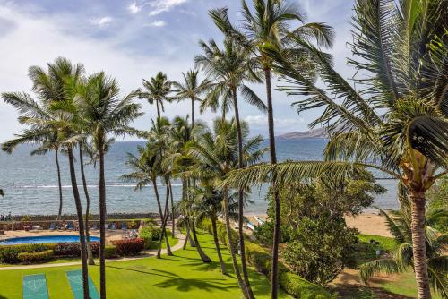 a group of palm trees next to a swimming pool at Oceanfront Modern & Elegant Vistas in Kihei