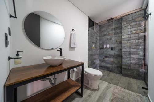a bathroom with a sink and a toilet and a mirror at Epic Suites x Ahead in Pereira