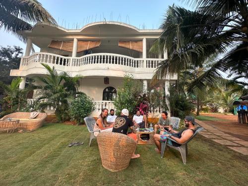 a group of people sitting around a table in front of a house at SOLS Backyard in Arambol