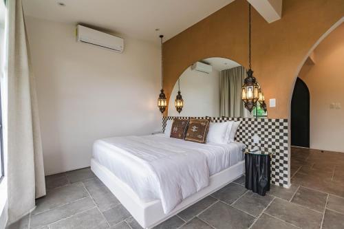 a bedroom with a white bed and a mirror at Domo Nosara in Nosara